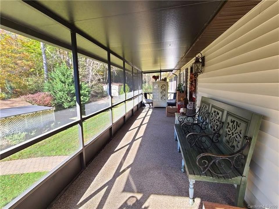 Long screened porch with a bench along the house wall, looking out over the yard.
